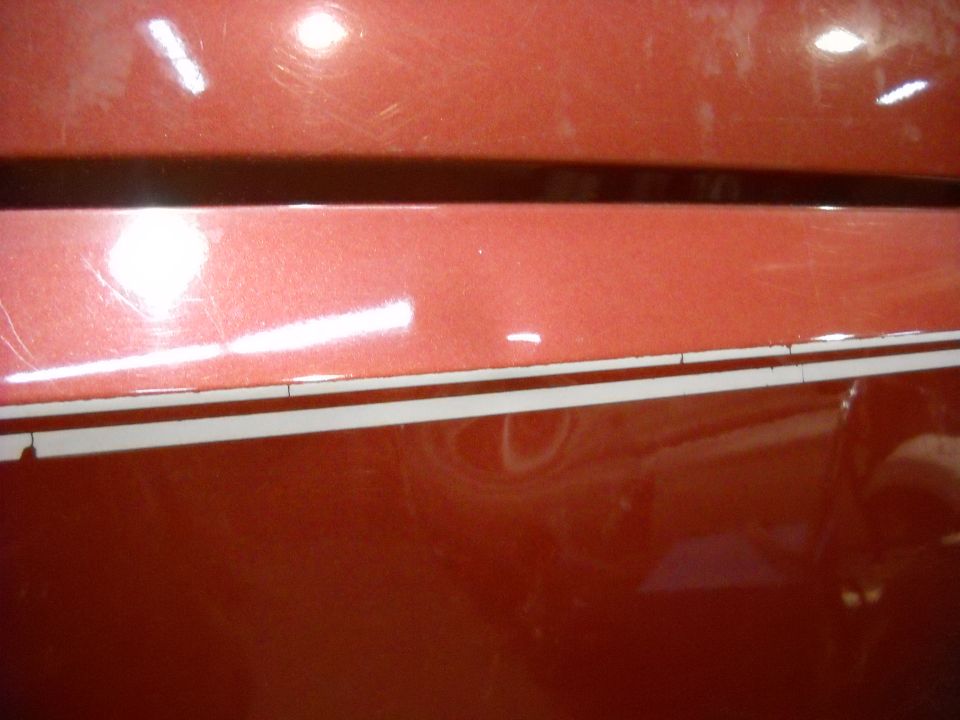 Red vehicle side panel with a dent and pinstriping