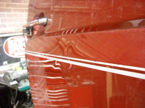 1993 Ford C-150 (Centurion Conversions) - Close-up of a red truck door showing a chrome handle and a white pinstripe detail.