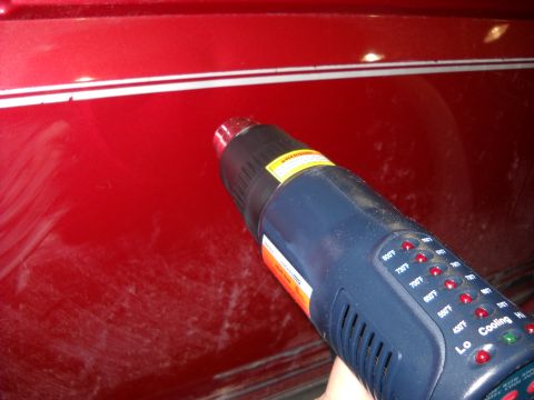 1993 Ford C-150 (Centurion Conversions) - Using a heat gun on a red vehicle panel with pinstripes.