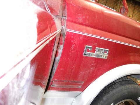 1993 Ford C-150 (Centurion Conversions) - The fender emblem on a red pickup truck reads C150 CLASSIC, with visible damage on the body panel.