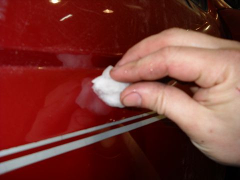 1993 Ford C-150 (Centurion Conversions) - A hand cleans a red vehicle's side, revealing a white stripe detail.