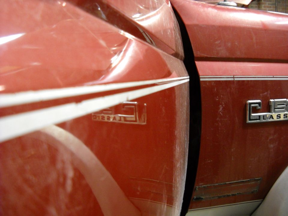 Close-up of a red pickup truck's side panel with a dent. Shows 'CLASSIC' emblem