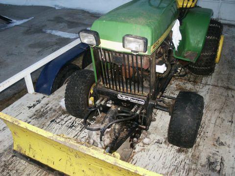 1966 Ford Bronco - A green and yellow John Deere tractor is equipped with a snow plow and chains on its rear tires.