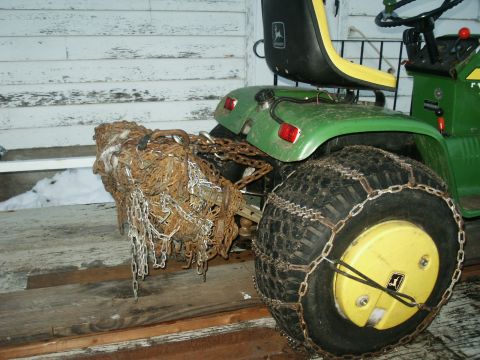 1966 Ford Bronco - A green John Deere tractor is parked with chains on its rear tire and a large bundle of chains attached to the hitch.