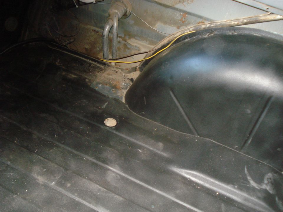 Interior floor and wheel well of a vehicle. Some rust is visible