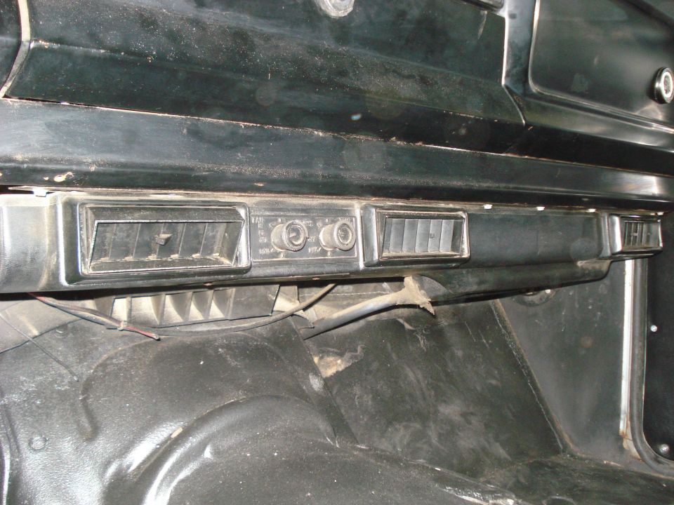 Dashboard with air vents and knobs. Floor is visible below