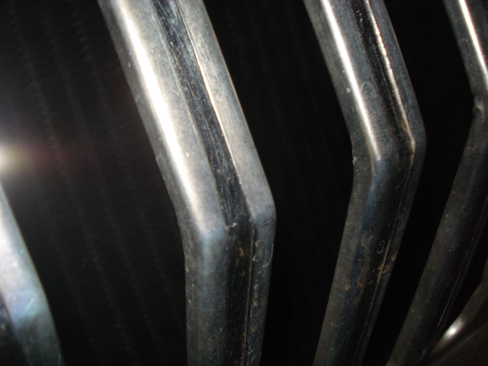 Close-up of bent chrome grille bars against a dark background