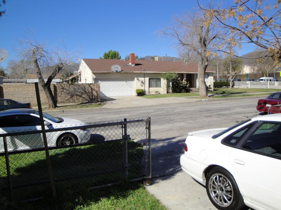 White sedan parked on a residential street, rear view, showing its taillight and trunk