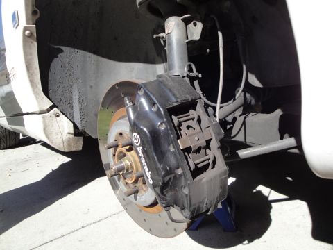 1993 Ford Taurus - Close-up view of a vehicle's front brake assembly, a black Brembo caliper and a drilled rotor.