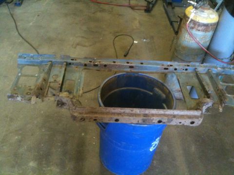 1993 Ford Bronco - Rusted vehicle frame section sits on a blue bucket in a workshop.