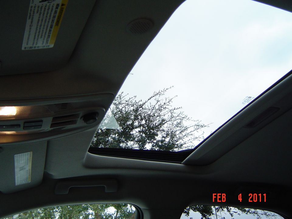 Open sunroof viewed from inside vehicle with tan headliner and overcast sky