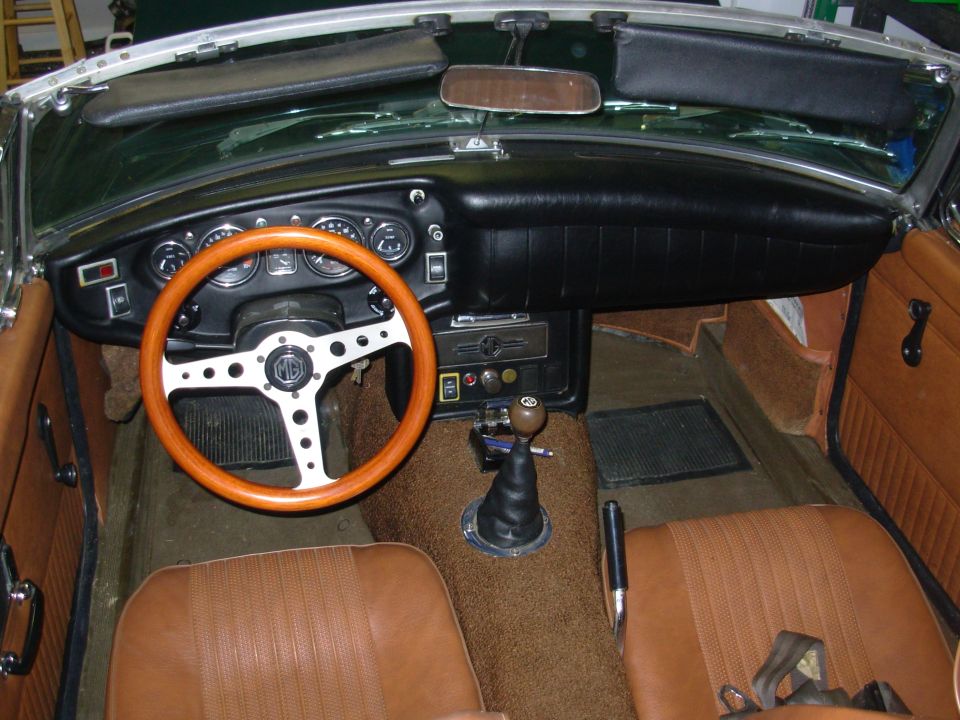 MG convertible interior with wood steering wheel, black dash, and tan leather seats