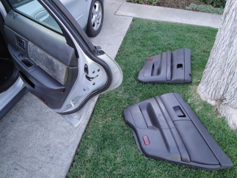 2003 Ford Taurus - Removed car door panels are laid out on the grass beside a tree.