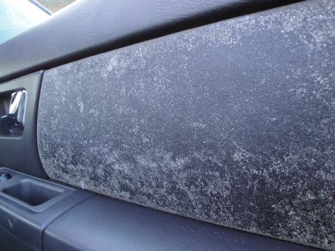 2003 Ford Taurus - Close-up of a discolored and scratched car interior door panel, showing wear and tear.