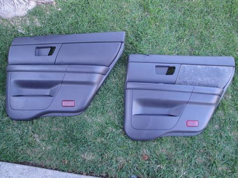 2003 Ford Taurus - Two dark gray car door panels are displayed on a grassy surface, showing their interior side details.