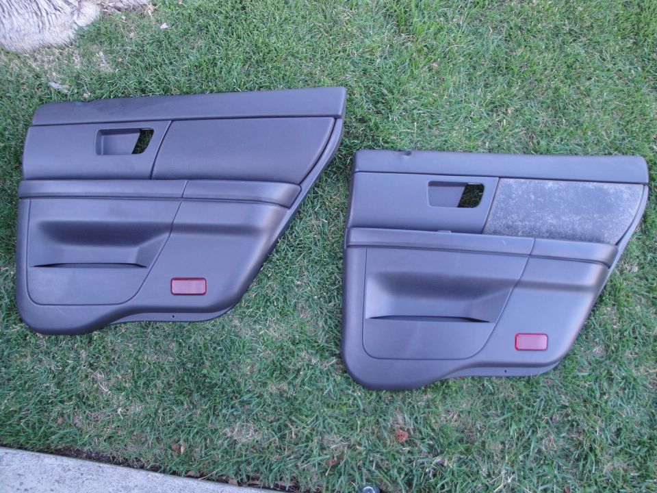 Pair of black rear door panels with red reflectors laid on grass