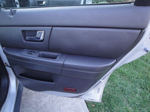 2003 Ford Taurus - Interior view of a car's rear door panel, a textured insert and chrome door handle.