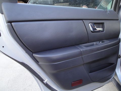 2003 Ford Taurus - Close-up of a car's interior rear door panel, showing the door handle and window controls.