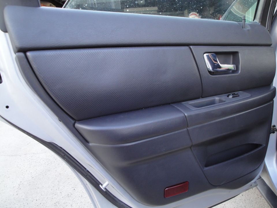 Interior rear door panel with a chrome door handle and window controls