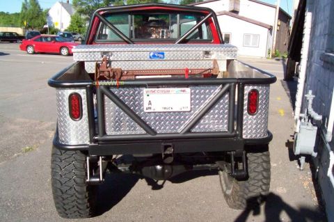 1989 Ford Bronco - This modified pickup truck features a custom diamond plate bed, a roll cage, and large off-road tires, seen from the rear.