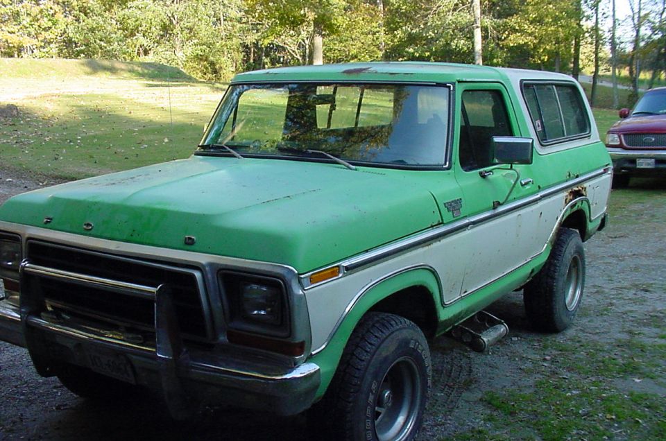 Green and white 1978 Ford Bronco with rust spots and a chrome bumper