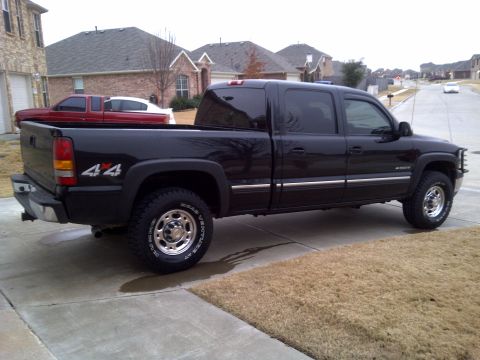 2002 Chevrolet Silverado 1500 - Side view of a black 2002 Chevrolet Silverado 1500 crew cab pickup truck with a red pickup truck behind it.