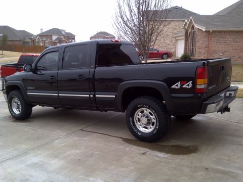 2002 Chevrolet Silverado 1500 - A black pickup truck is parked in a driveway with a red truck visible behind it.