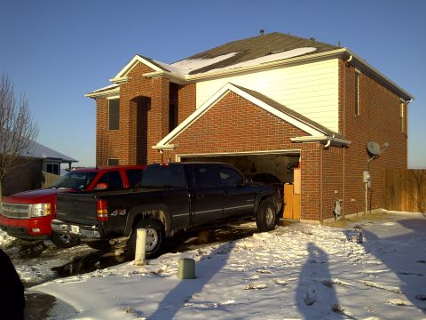 2002 Chevrolet Silverado 1500 - Two pickup trucks, a black Silverado and a red Avalanche, are parked in a driveway covered in snow.
