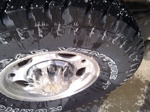 2002 Chevrolet Silverado 1500 - A close-up of a tire covered in ice and icicles, indicating cold weather conditions.