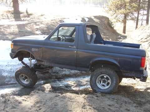 1988 Ford Bronco - This 1988 Ford Bronco is shown navigating a challenging off-road course with uneven terrain.