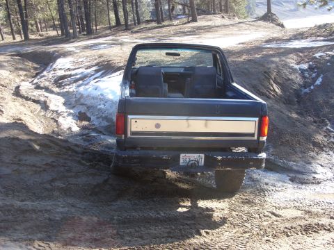 1988 Ford Bronco - This Ford Bronco is parked on a dirt path with patches of snow and mud.