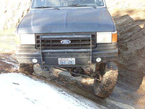 1988 Ford Bronco - This 1988 Ford Bronco is captured from the front, navigating a muddy and snowy trail.