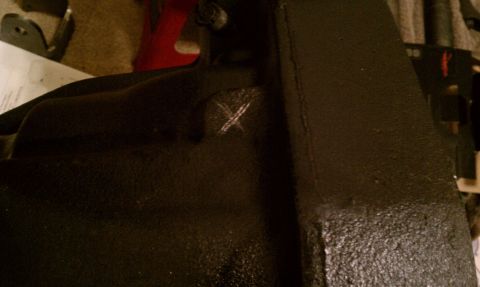 1990 Ford Bronco - A close-up view of a black painted metal part with a white X mark.