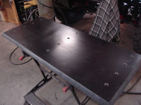 1989 Ford Bronco - Workbench with a dark metal top, resting on a black metal frame with red handles.