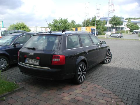 2003 Audi A6 - A black Audi A6 Avant wagon is parked on a brick surface, with another car to its left and buildings in the background.