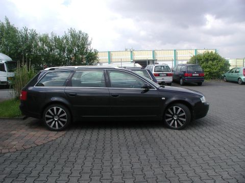2003 Audi A6 - Side view of a dark Audi A6 Avant parked on paver stones with other vehicles nearby.