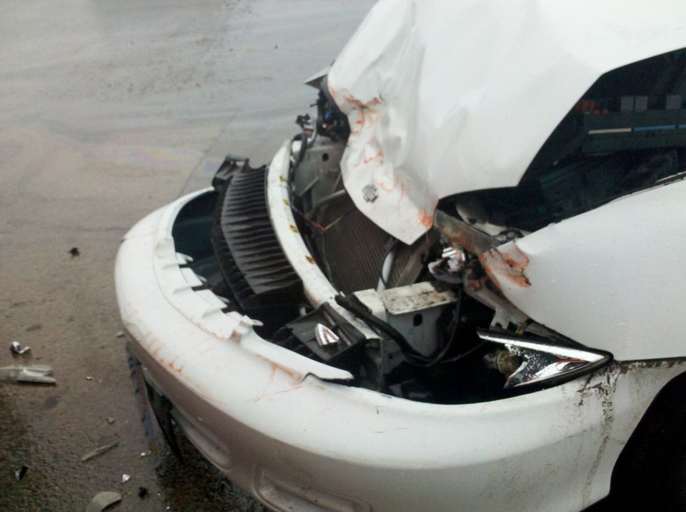 White SUV front end severely damaged after a collision. Water on the road