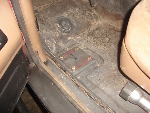 1989 Ford Bronco - A metal plate with markings is bolted to the floor of the vehicle's interior.