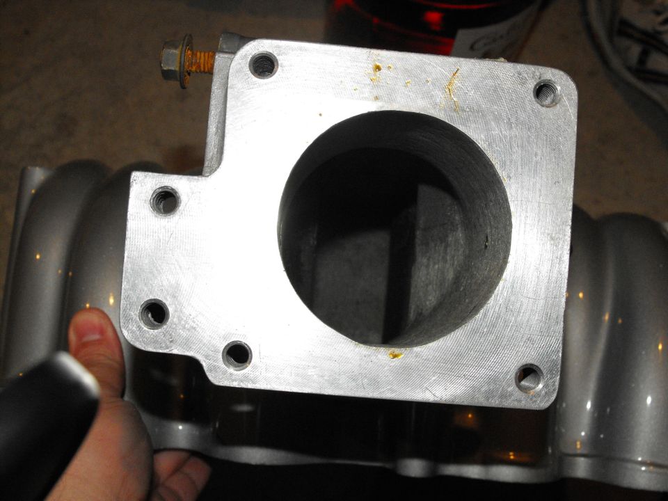Close-up of a throttle body with a hand holding it