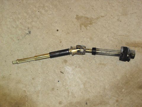 1994 Ford Bronco - A steering shaft assembly with two universal joints and black rubber isolators is shown against a concrete background.
