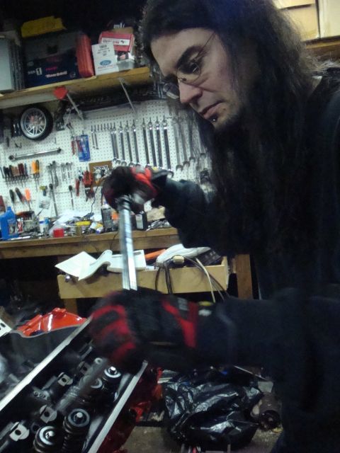 1989 Ford Bronco - Mechanic works on engine valve train components in a garage.