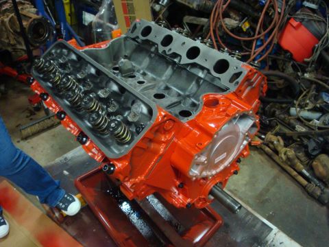 1989 Ford Bronco - A freshly painted orange V8 engine block is shown on a stand, with valve springs exposed.