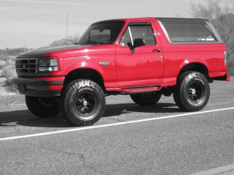 1996 Ford Bronco - This red 1996 Ford Bronco features a contrasting black hood and roof, and is shown from a 3/4 front angle.