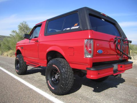 1996 Ford Bronco - This red Ford Bronco is shown from the rear-three-quarter view with a spare tire carrier mounted on the back.