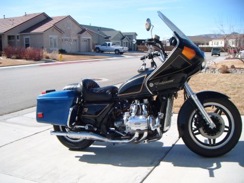 1982 Toyota 4Runner - A black motorcycle with gold trim and blue saddlebags is parked on a suburban street.