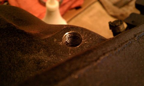 1990 Ford Bronco - A close-up view of a threaded hole on a metal part, with a water bottle visible in the background.