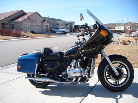 1982 Toyota 4Runner - A black motorcycle with a large windshield and blue saddlebags is parked on a sidewalk in front of houses.