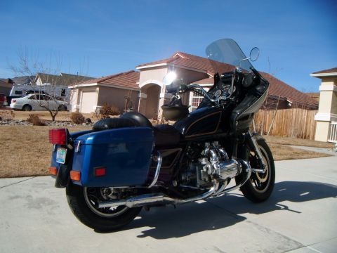 1982 Toyota 4Runner - A blue motorcycle with a large fairing and blue saddlebags is parked on a concrete driveway in front of a house.