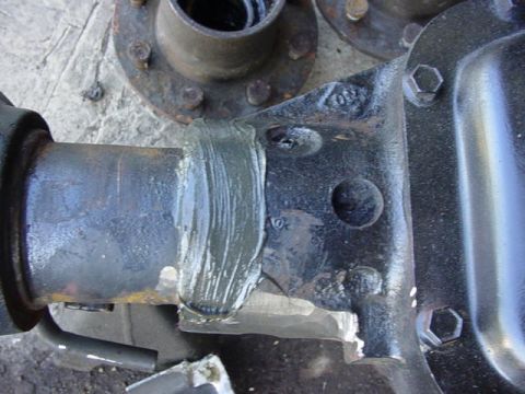 1992 Ford Bronco - Overhead close-up of a fresh, unpainted weld bead joining an axle tube to the cast differential housing, with the stacked filler passes and…
