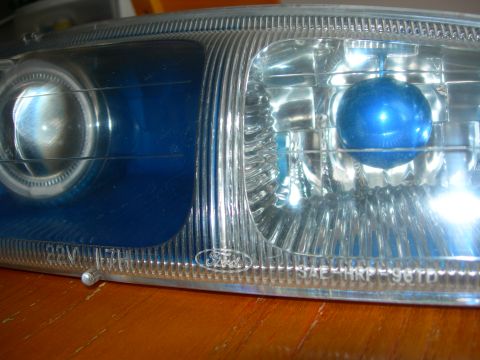 1984 Ford Bronco - Close-up of a Ford headlight assembly, showing the blue bulb and internal reflector details.